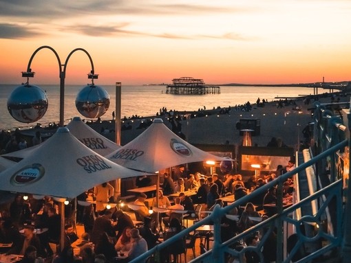 People enjoy drinks at Ohso Social bar on Brighton seafront at sundown