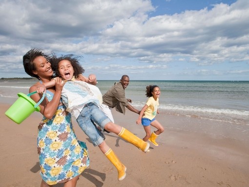 Family playing on the beach in the sunshine, Northumberland