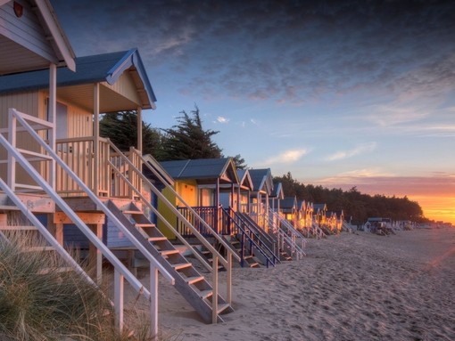 Sunset at high tide behind the old beach huts on coast