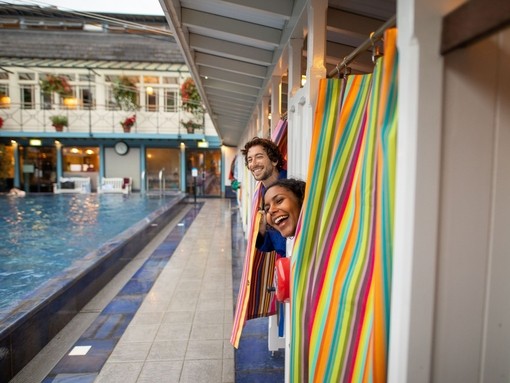 Man and woman peek out of changing rooms before going for a swim