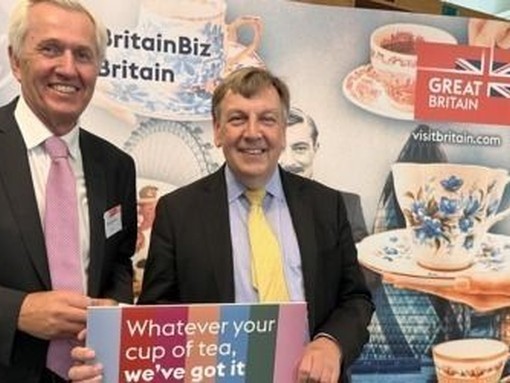 Nick De Bois posing in front of VisitBritain promotional materials