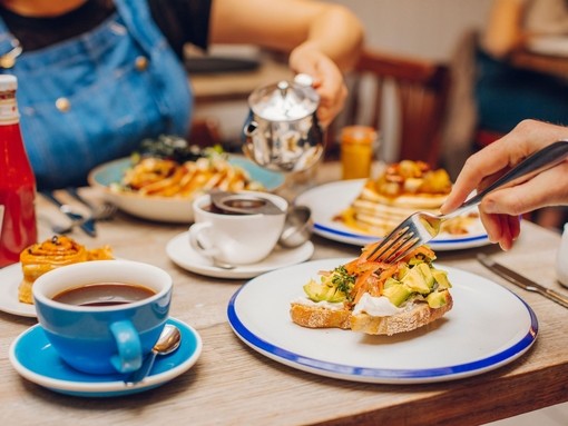 Hands eating plates of food at a restaurant