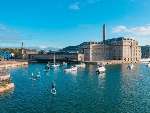 People paddleboarding near a dock in Plymouth