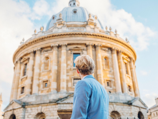 Man looking up at a historical building with domed shaped roof.