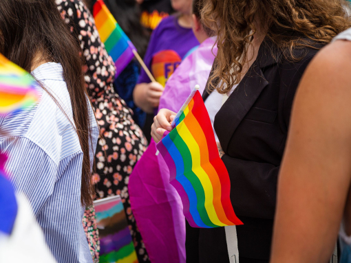 Crowds of people holding rainbow flags at a Pride Parade in London.
