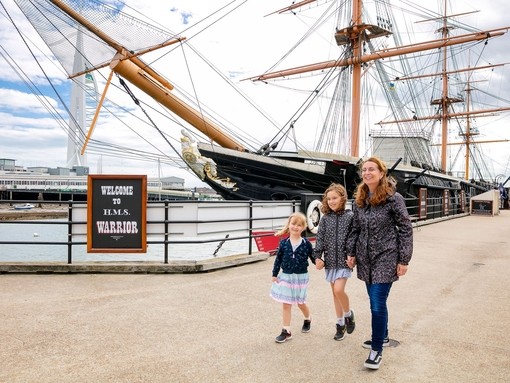 A family walking alongside a ship at a dock