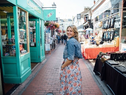 Smiling woman in denim jacket standing between shops