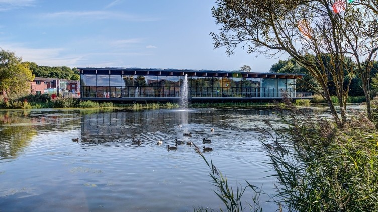 View of lake complete with fountain and ducks to a glass fronted building