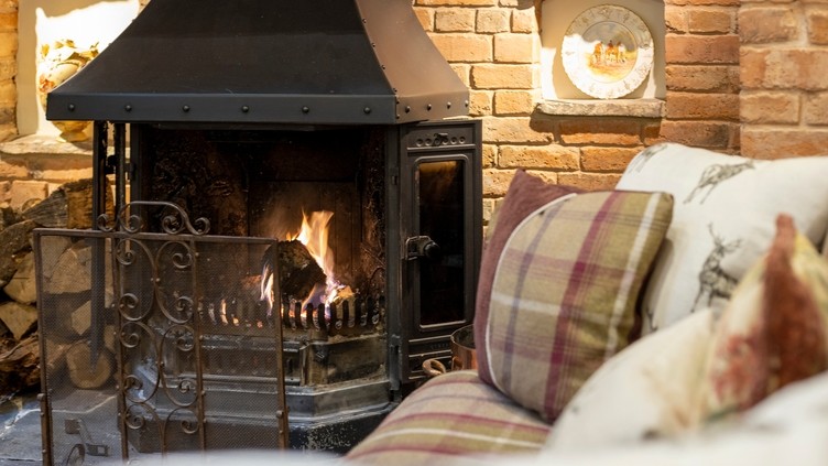 View of the lounge at Horseshoe Cottage Farm, Leicestershire close-up of the inglenook fireplace and tartan patterned sofas. Silver winner of the B&B and Guest House of the Year in the VisitEngland Awards for Excellence 2022