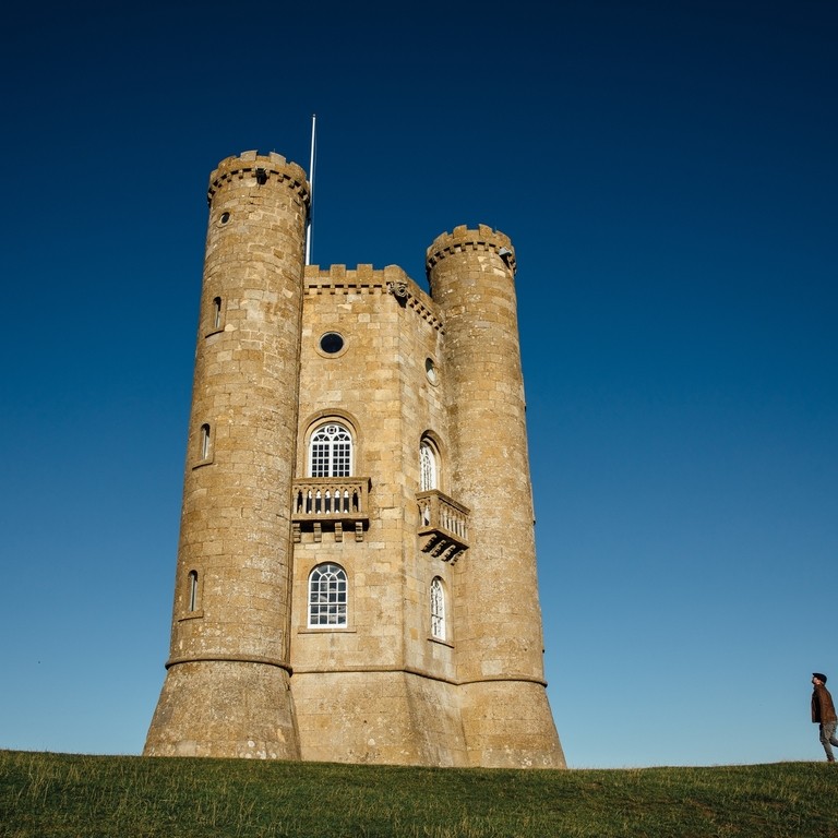 Distant view of man walking towards tall stone tower.