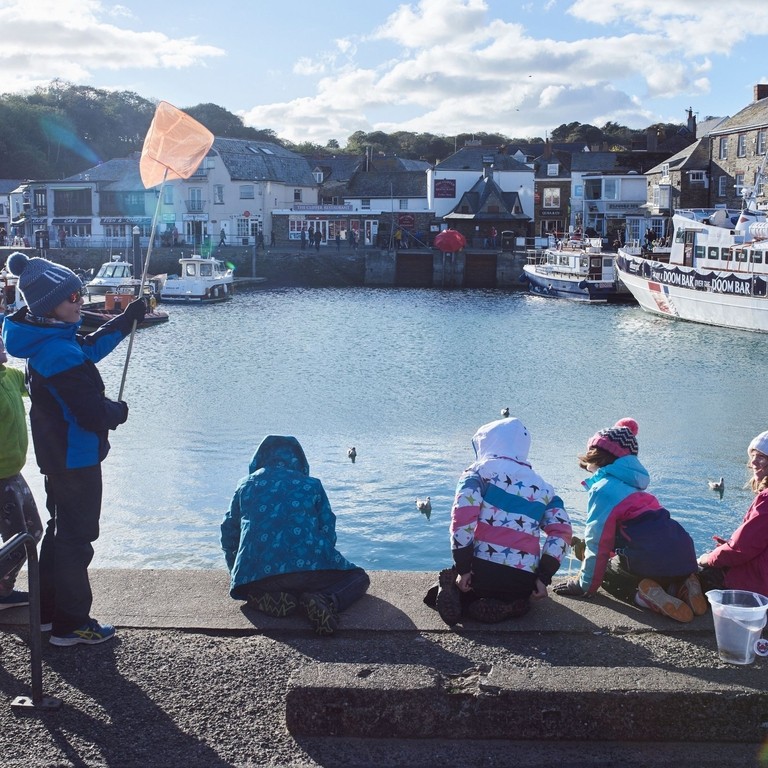Children on harbour wall fishing for crabs