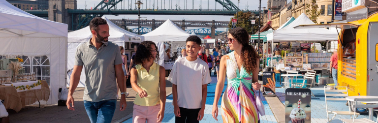 A family visit a Sunday market by the river Tyne in Newcastle upon Tyne