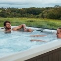 Couple relaxing in a hot tub overlooking countryside