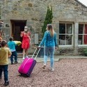 Family arriving at the exterior of a Bed and Breakfast home, met by host